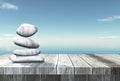 3D balancing pebbles on a wooden table looking out to the ocean Royalty Free Stock Photo