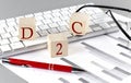D2C written on a wooden cube on the keyboard with chart on grey background Royalty Free Stock Photo