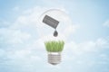 3d closeup rendering of electric bulb with black oil barrel tipped and spilling oil drop on green grass, all inside the