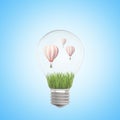 3d closeup rendering of electric bulb with green grass and three striped hot-air balloons inside on light-blue Royalty Free Stock Photo