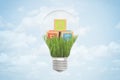 3d closeup rendering of lightbulb with three ABC blocks lying on green grass inside bulb against blue sky with clouds.