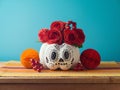 DÂ­a de los Muertos day of the dead holiday concept. Sugar skull Halloween pumpkin and Mexican party decorations on wooden table