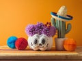 DÂ­a de los Muertos day of the dead holiday concept. Sugar skull Halloween pumpkin and Mexican party decorations on wooden table