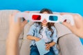3D glasses in hands in front of smiling to camera little relaxing on couch on blue background. Wearing stylish
