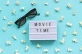 3D glasses, popcorn and lightbox text Movie time on blue paper background. Top view Template Concept cinema movie and Royalty Free Stock Photo