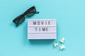 3D glasses, popcorn and lightbox text Movie time on blue paper background. Top view Template Concept cinema movie and Royalty Free Stock Photo