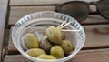 Appetizing green olives in white plate on wooden background. Rustic style