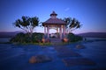 3D illustration of a gazebo with a dining table set for a romantic evening meal in a garden by a lake