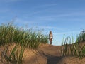Illustration of a lone woman walking along a sand dune in early morning light
