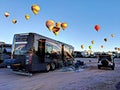 3D illustration of a luxurious Entegra motorhome parked underneath a flight of hot air balloons