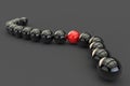 3D illustration. A red ball has infiltrated a chain of black balls. Alien object among many identical