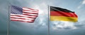 Two state flags of the united states of america and germany, facing each other and moving in the wind in front of