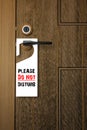 3D : Illustration of white Paper signboard with Please do not disturb text hanging on a handle of wooden door resort or hotel. Royalty Free Stock Photo