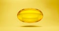 3d illustration of a yellow capsule with a small omega, floating on a yellow background with reflection and shadow Royalty Free Stock Photo