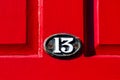 Oval number 13 on a bright red wooden front door