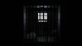 3D model of a solitary prison cell behind bars with a bed and a table and a window with light Royalty Free Stock Photo