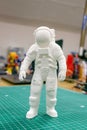 3D printed astronaut, cosmonaut, robot on the background of devices and laptop. Spaceman model printed on automatic three