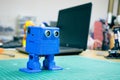 3D printed Funny blue robot on the background of devices and laptop. Robot model printed on automatic three dimensional 3d Royalty Free Stock Photo