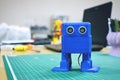 3D printed Funny dancing blue robot on the background of devices and laptop. Robot model printed on automatic three dimensional 3d Royalty Free Stock Photo