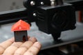 3D printed model house with a real 3d printer machine on its background performing some 3d print works Royalty Free Stock Photo