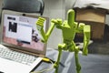 A 3d-printed robot with articulated limbs standing next to a laptop