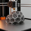 A 3D printer creates a complex, geometric lattice structure resembling a geodesic dome