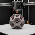 A 3D printer creating a complex geometrical object. The machine\'s nozzle is actively