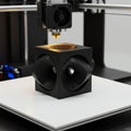 3D printer creating a geometric object with hollow sections. The object, made of black Royalty Free Stock Photo
