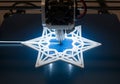 A 3D printer is creating a geometric star-shaped object on a blue printing Royalty Free Stock Photo