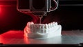 3 D printer creating white dental model with red light glow printing technology Royalty Free Stock Photo