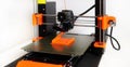 3D Printer in operation with orange filament on a white background Royalty Free Stock Photo