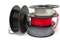 3D Printer Plastic Filament. Spools of black, red, grey, white thermoplastic wires for 3d printing close up