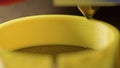 3D printer printing a part made of yellow plastic, close-up view