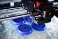The 3D printer prints the details of the blue plastic.
