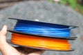 3D printing filament spools on hand. Blue and orange 3D Printer filaments for additive manufacturing