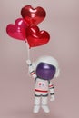 3D render An astronaut holds several heart-shaped balloons. Cartoon character astronaut floating in space with red tiny hearts. 3d