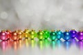 3d render of beautiful metallic rainbow xmas baubles on a silver bokeh background