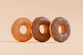 3D Render - Donuts stacked in different styles viewed at an oblique angle. Chocolate donuts with icing sprinkle on top.