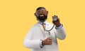 3d render. Happy doctor toy, african cartoon character wears white coat and holds stethoscope. Clip art isolated on yellow