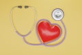 3D render red heart with a medical stethoscope isolate on yellow background. Blood pressure control. Heart and heartbeat.
