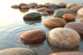 3d render of smooth stone pebbles with earth tones and gentle water wave effect Royalty Free Stock Photo