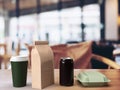 3d render of a takeout lunch box, beverage can, paper coffee bag and coffee mug on a wooden table in a blurred Royalty Free Stock Photo