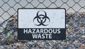 3D rendered illustration of hazardous waste sign on chain link fence. Landfill in background