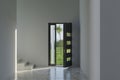 anthracite opened entrance door and marble tiled floor in front of green lawn with palm tree