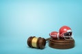 3d rendering of ball and helmet for American football on sounding block with judge gavel lying beside on light-blue