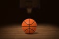 3d rendering of a basketball on the wooden floor in a dimly lit gym with a blurred image of the basket in the background