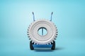 3d rendering of big grey wheel gear on blue hand truck which is standing in half-turn on light-blue background with much