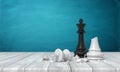 3d rendering of a black chess king standing above a broken white king figurine on a wooden desk background.