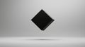 A 3D rendering of a black cube suspended in mid-air against a light gray background. Royalty Free Stock Photo