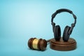 3d rendering of black headphones standing upright on sounding block with judge gavel beside on light-blue background.